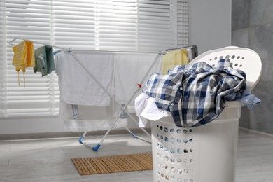 Photo of Plastic laundry basket overfilled with clothes in bathroom. Space for text