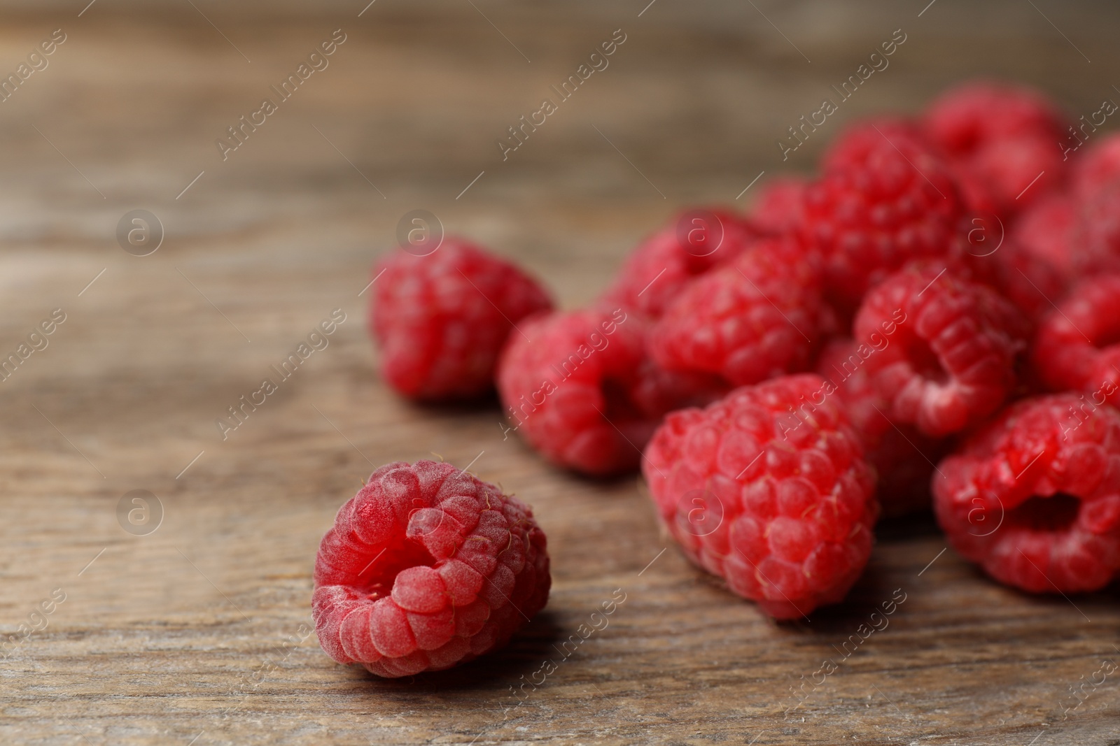 Photo of Heap of delicious ripe raspberries on wooden table, closeup