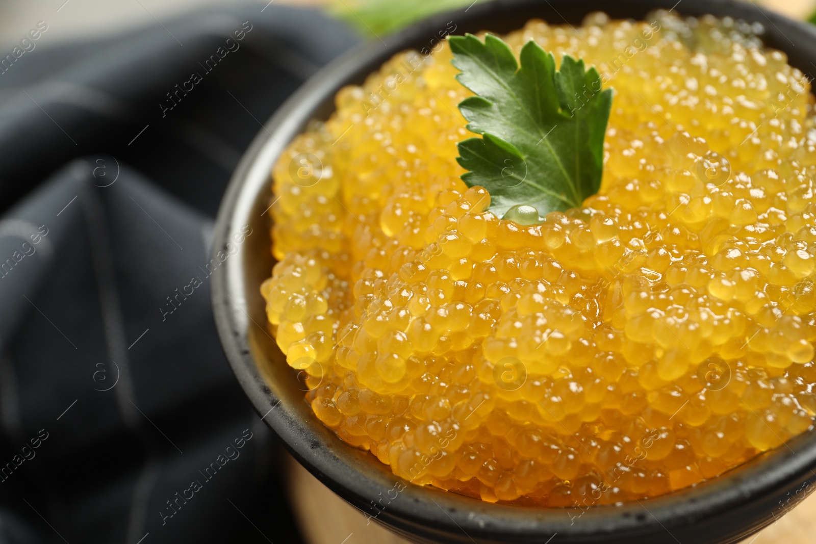 Photo of Fresh pike caviar and parsley in bowl on table, closeup