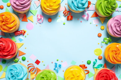 Photo of Colorful birthday cupcakes on light blue background, flat lay. Space for text