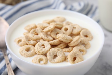 Photo of Breakfast cereal. Tasty corn rings with milk in bowl on table, closeup