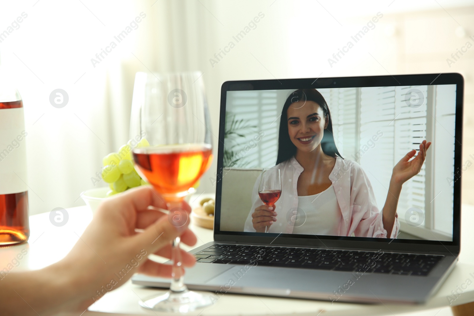 Photo of Friends drinking wine while communicating through online video conference at home. Social distancing during coronavirus pandemic