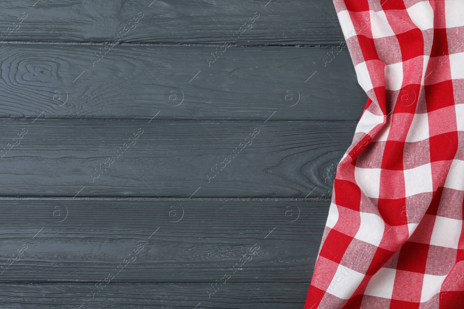 Photo of Checkered picnic blanket on color wooden background, top view. Space for text