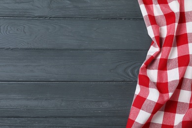 Photo of Checkered picnic blanket on color wooden background, top view. Space for text