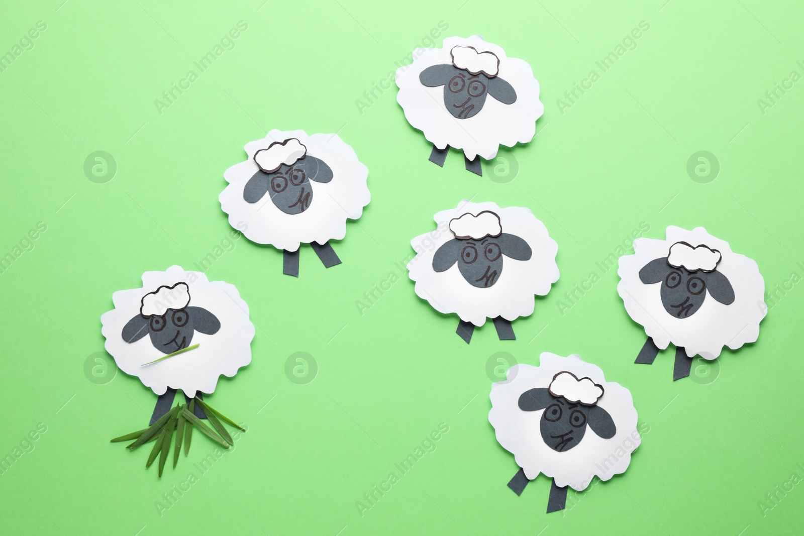 Photo of Paper sheeps on green background, flat lay. Concept of jealousy