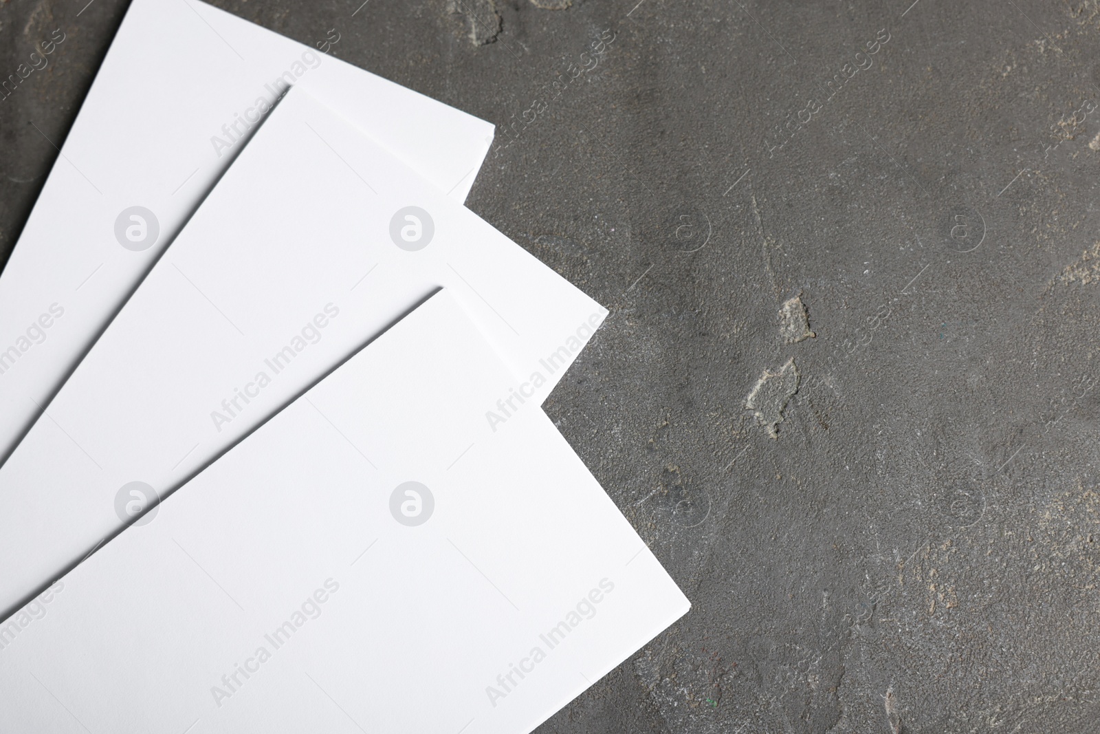 Photo of Blank paper sheets on grey textured background, top view. Mockup for design