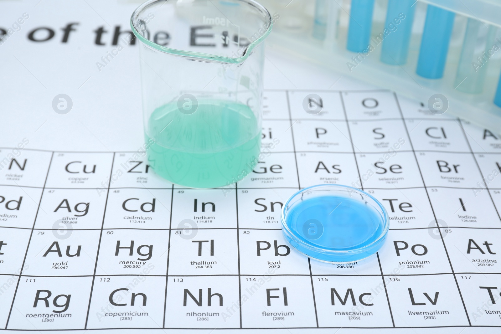 Photo of Beaker and Petri dish on periodic table of chemical elements, closeup