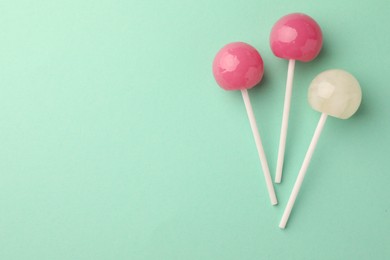 Photo of Tasty lollipops on turquoise background, flat lay. Space for text