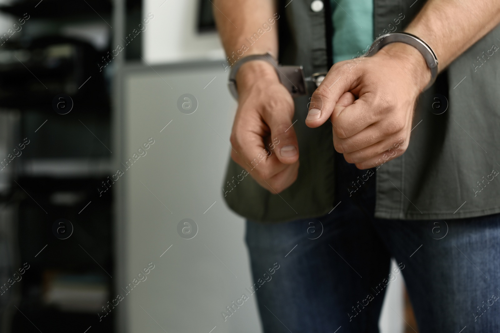 Photo of Man detained in handcuffs indoors, space for text. Criminal law