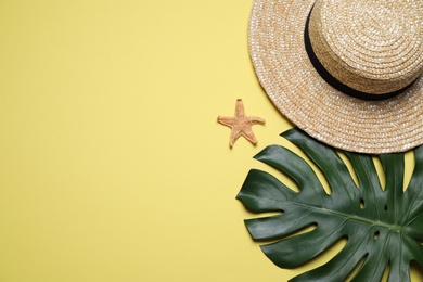 Photo of Straw hat, tropical leaf and starfish on yellow background