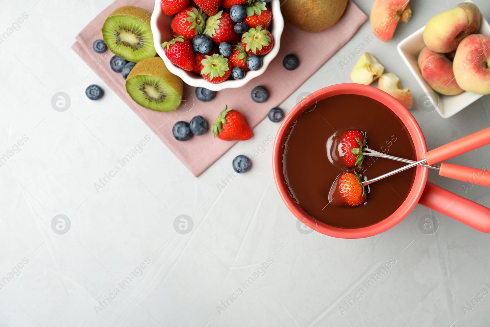 Photo of Flat lay composition with chocolate fondue in pot and fresh fruits on grey table. Space for text