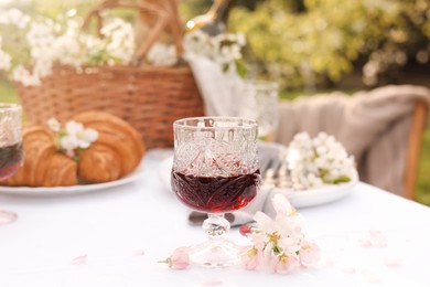 Stylish table setting with beautiful spring flowers, wine and croissants in garden