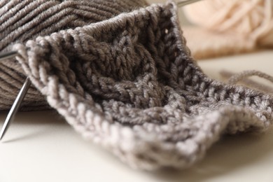Photo of Knitting, soft yarn and needles on beige background, closeup