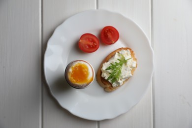 Photo of Breakfast with soft boiled egg on white wooden table, top view