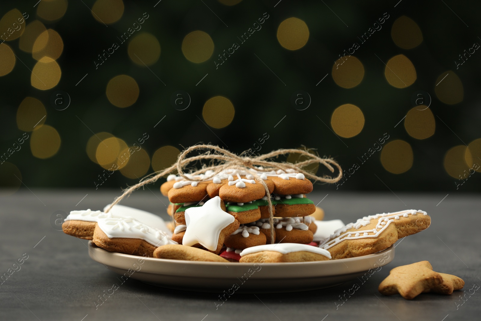 Photo of Decorated cookies on grey table against blurred Christmas lights