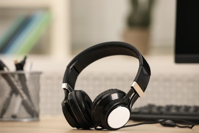 Photo of Modern headphones and computer on table indoors