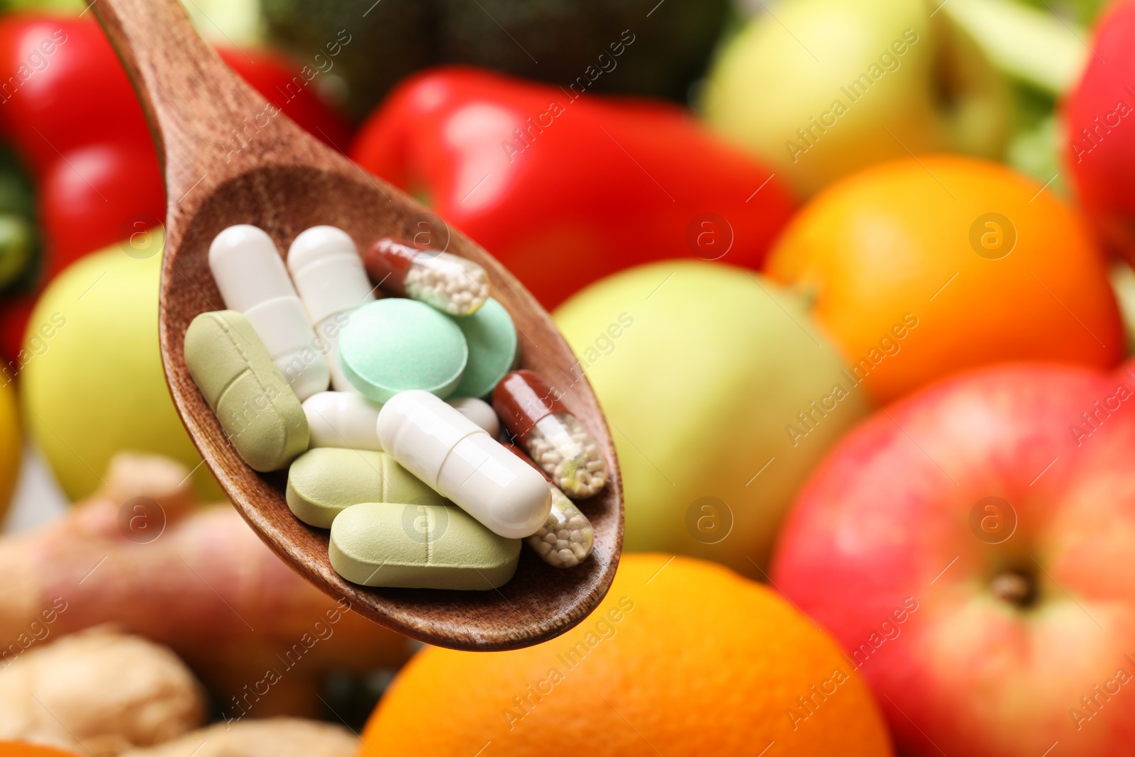 Photo of Different dietary supplements in wooden spoon near products, closeup. Space for text