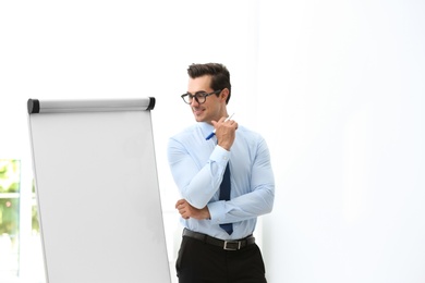 Professional business trainer near flip chart in office