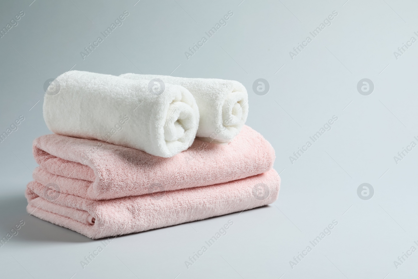 Photo of Stack of fresh towels on light background. Space for text