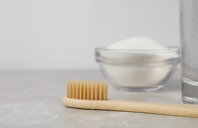 Photo of Bamboo toothbrush and glass bowl of baking soda on light table, space for text