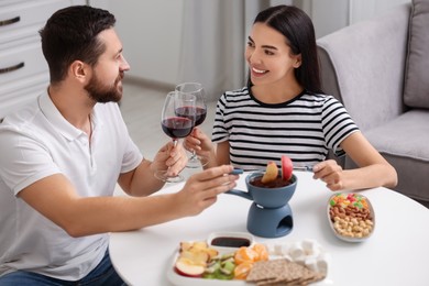 Photo of Affectionate couple enjoying chocolate fondue during romantic date at home