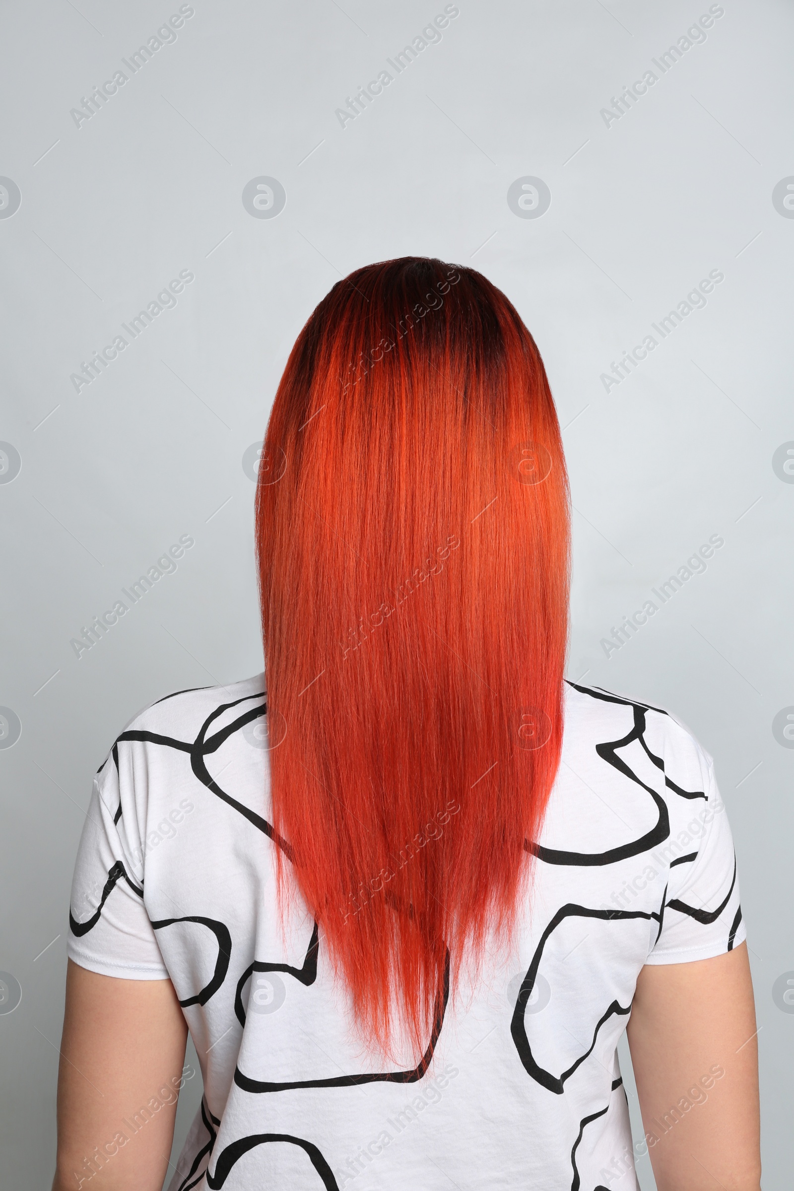 Photo of Woman with bright dyed hair on grey background, back view