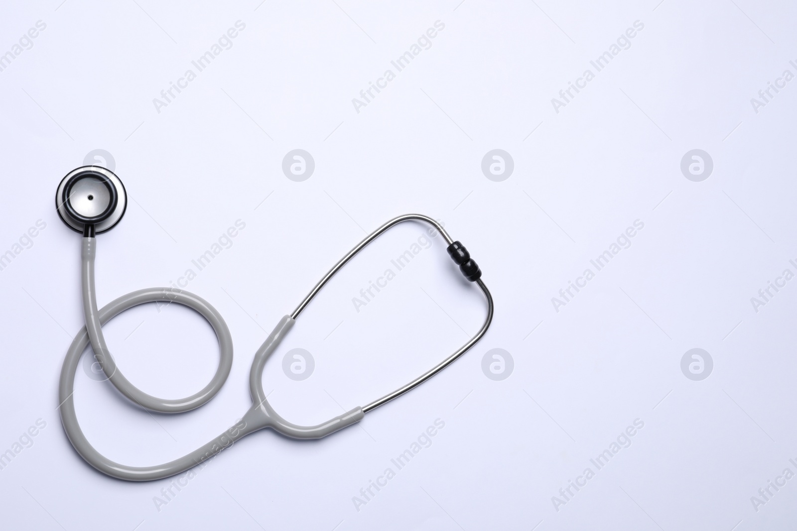 Photo of Stethoscope on white background, top view. Space for text