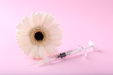 Cosmetology. Medical syringe and gerbera flower on pink background