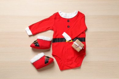 Photo of Christmas outfit for little baby on wooden background, flat lay