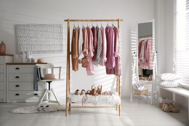 Photo of Rack with stylish women's clothes indoors. Interior design