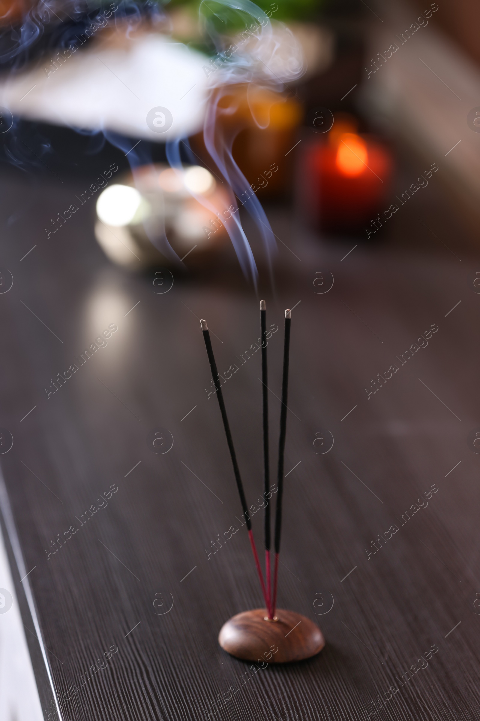 Photo of Incense sticks smoldering on wooden table in room