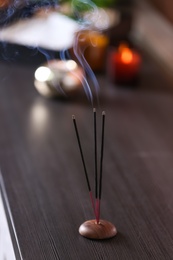 Incense sticks smoldering on wooden table in room