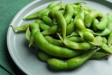 Photo of Plate of green edamame beans in pods on table, closeup