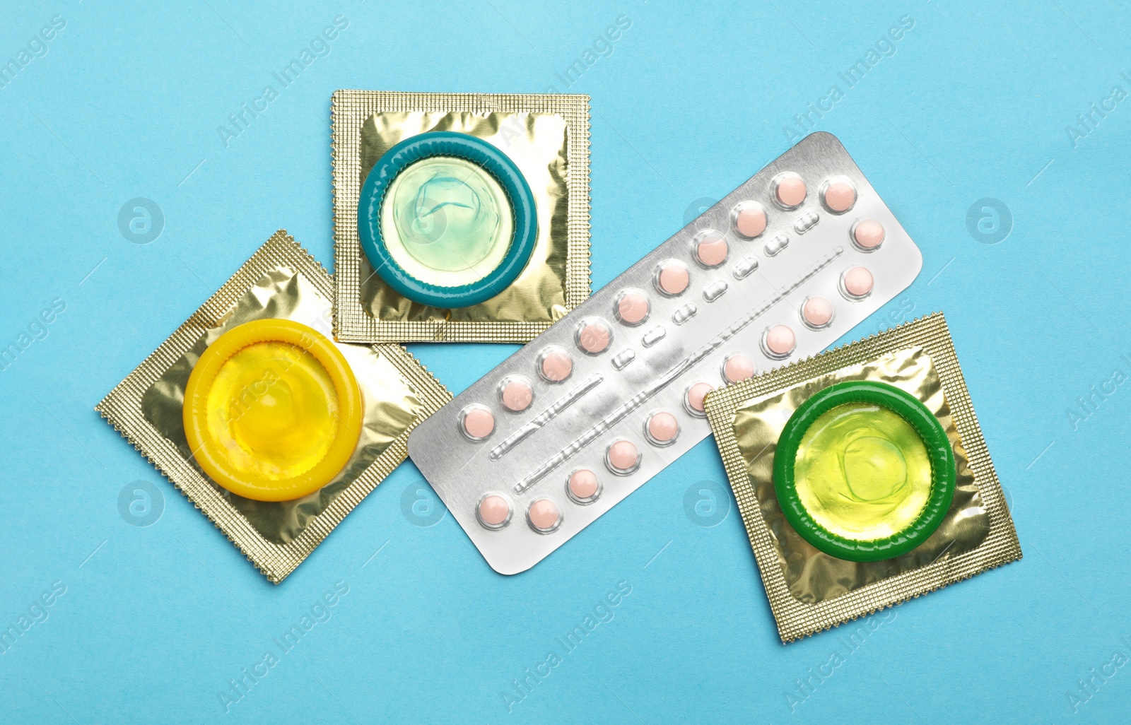 Photo of Condoms and birth control pills on light blue background, flat lay. Safe sex concept