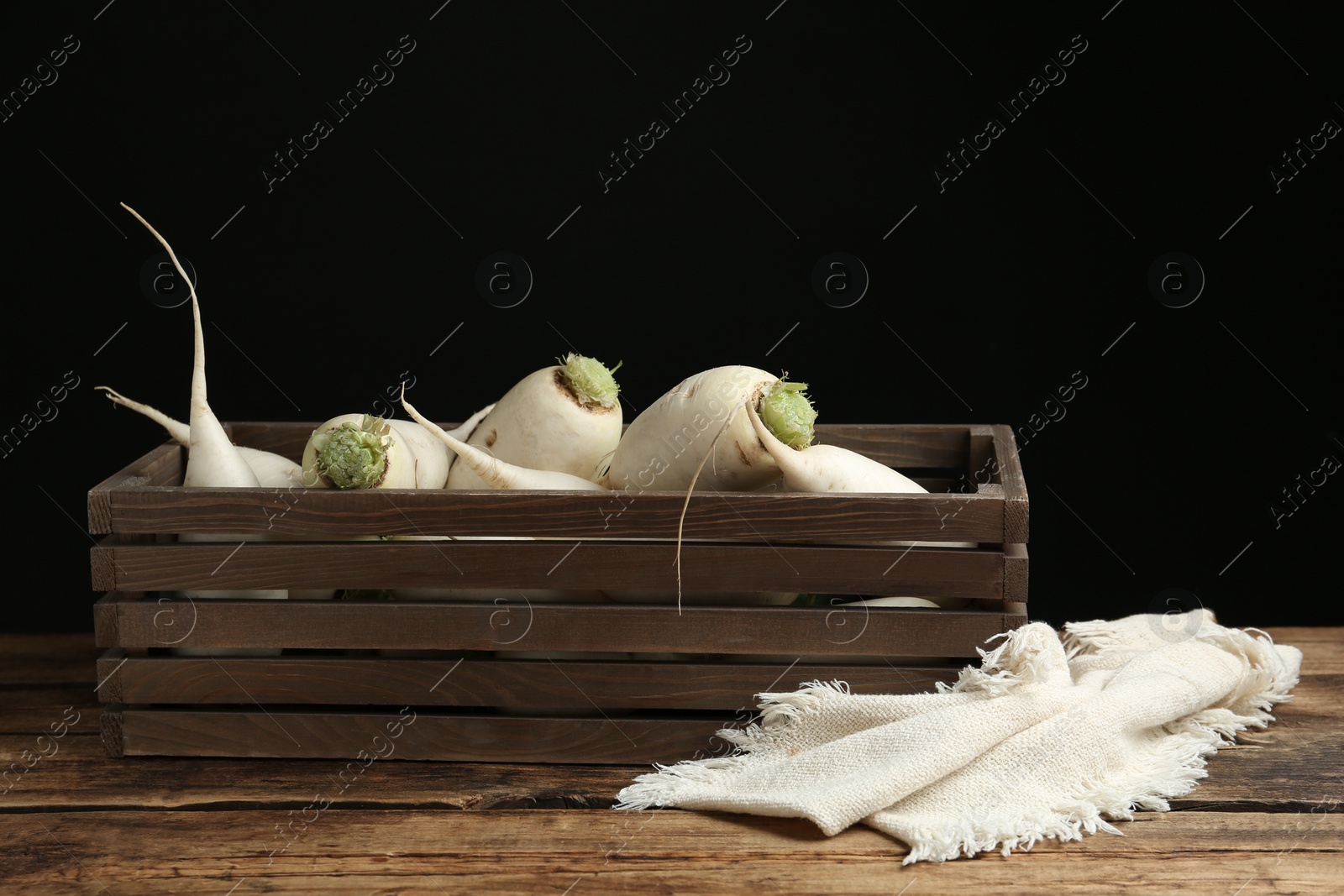 Photo of Crate with white turnips on wooden table