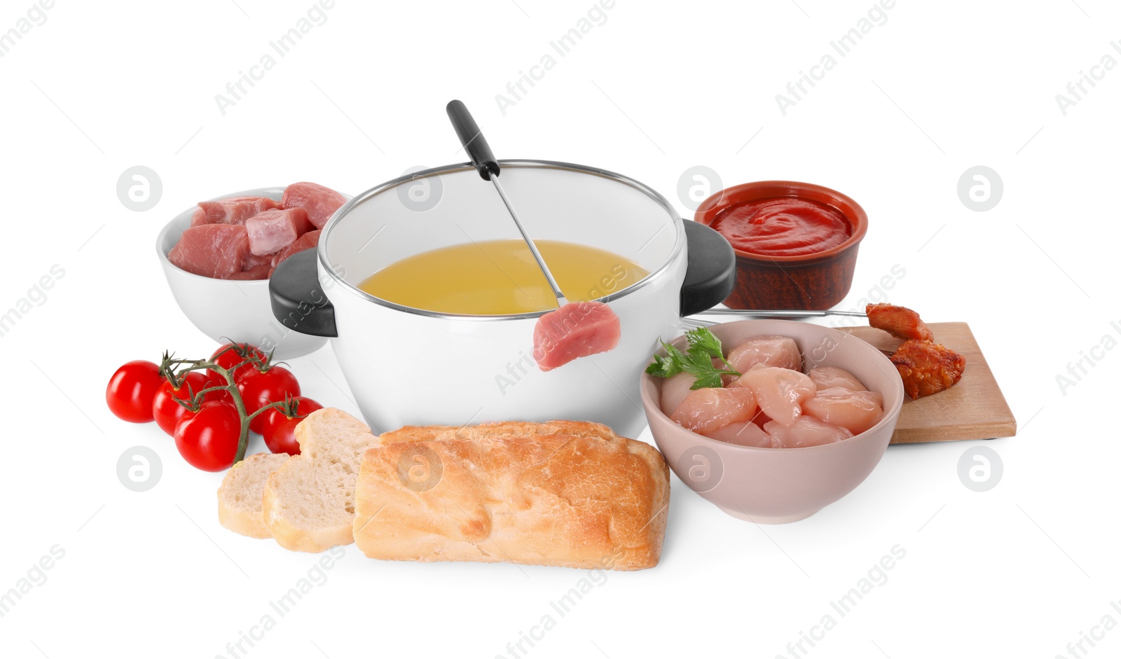 Photo of Fondue pot with oil, fork, raw meat pieces and other products isolated on white