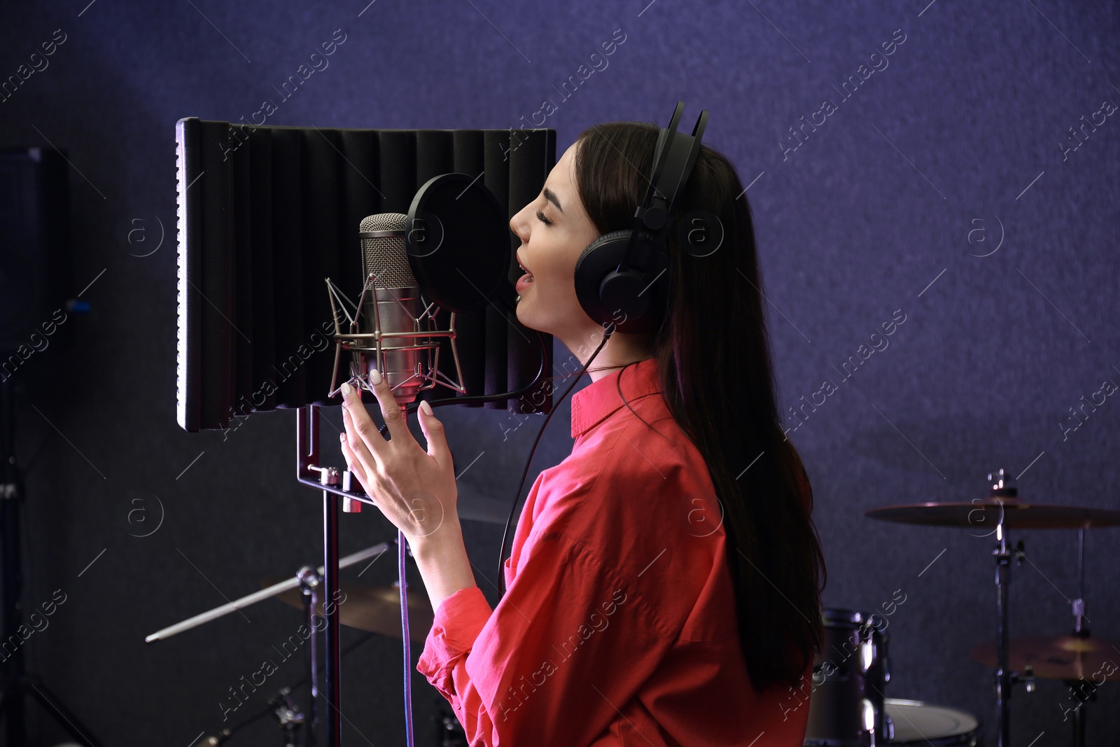 Photo of Young singer with microphone recording song in studio