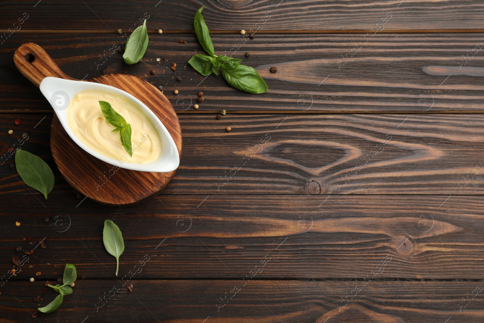 Photo of Tasty sauce in gravy boat, basil leaves and spice on wooden table, flat lay. Space for text