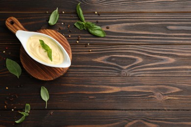 Tasty sauce in gravy boat, basil leaves and spice on wooden table, flat lay. Space for text