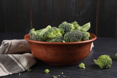 Bowl with fresh raw broccoli on black wooden table