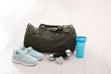Photo of Sports bag and gym equipment on white floor