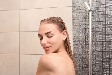 Beautiful young woman taking shower at home