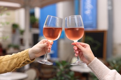 Photo of People clinking glasses with rose wine outdoors, closeup