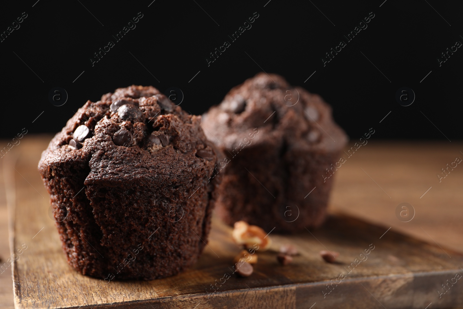 Photo of Delicious chocolate muffins on wooden table, closeup. Space for text