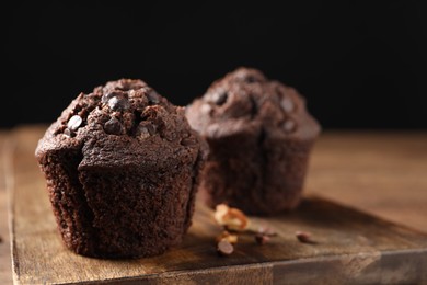 Photo of Delicious chocolate muffins on wooden table, closeup. Space for text