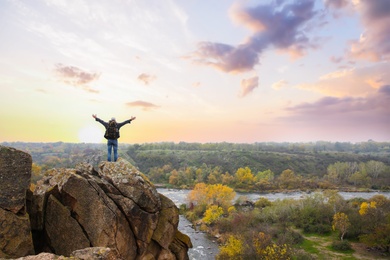 Hiker with travel backpack enjoying beautiful view near mountain river, back view