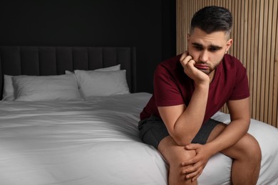 Photo of Sad man sitting on bed at home. Space for text