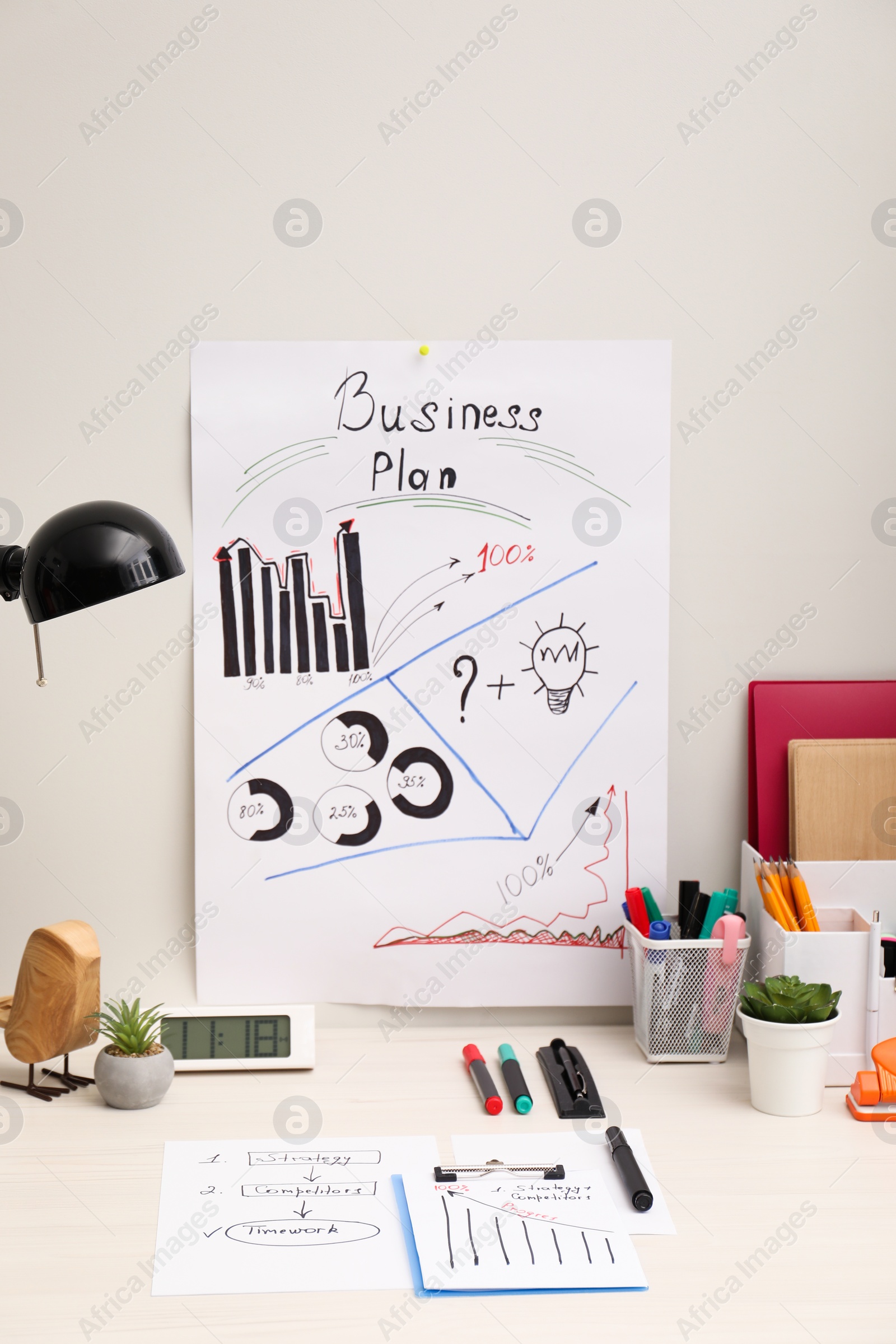 Photo of Business process planning and optimization. Workplace with plan, lamp, notebook and stationery on white wooden table