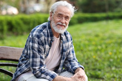 Photo of Portrait of happy grandpa with glasses on bench in park