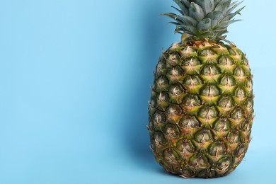 Whole ripe pineapple on light blue background, closeup with space for text